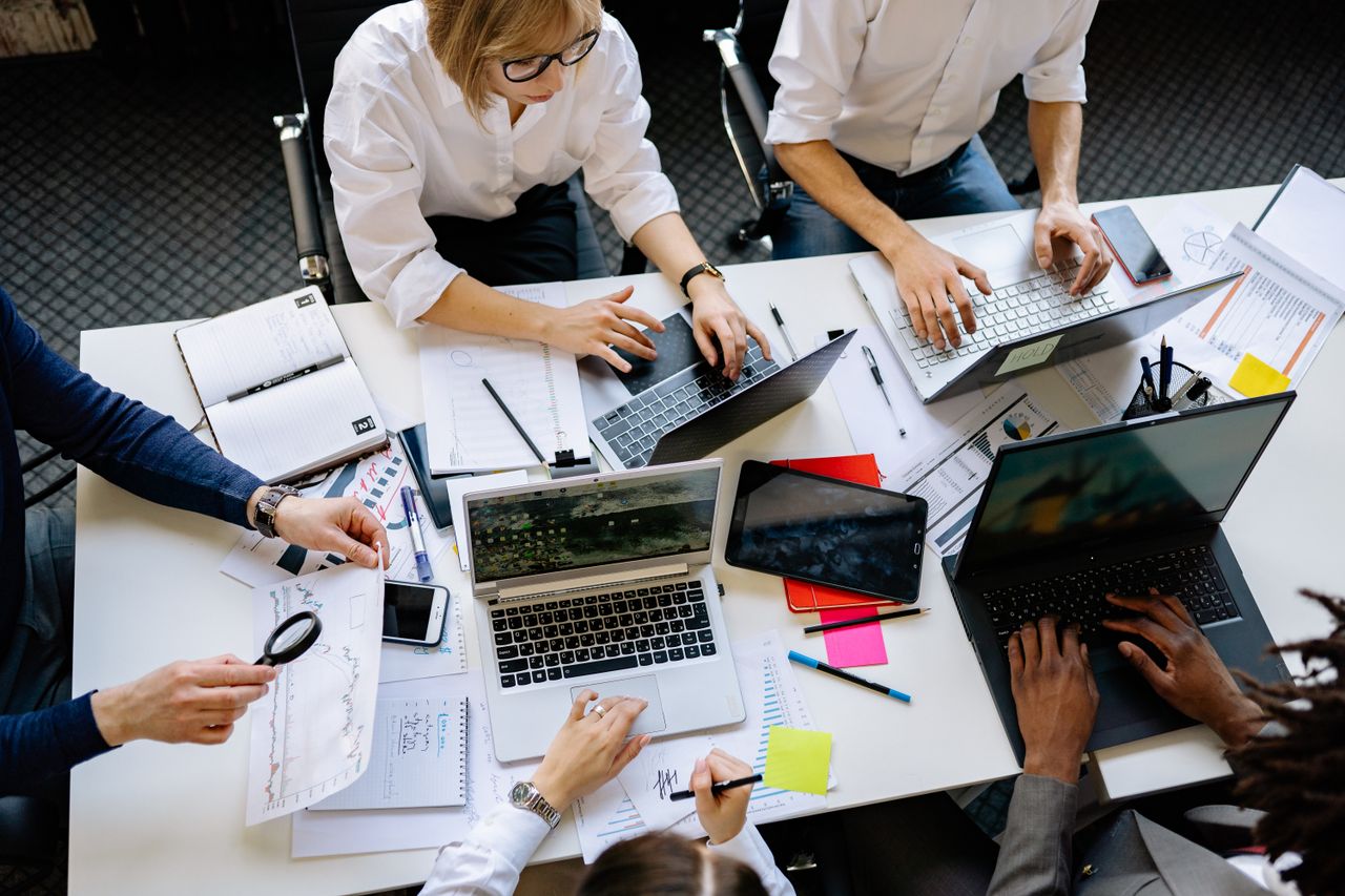 home-hero Overhead view of a corporate team collaborating with laptops and documents.